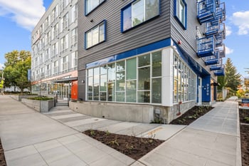 Modern building exterior of Keystone Apartments with gray siding, blue trim, and street-level win...