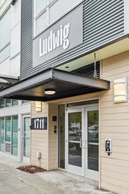 Main entrance of Ludwig Apartments featuring glass doors, a modern facade, and building number 1711.