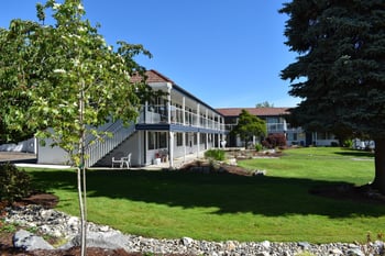 a large white building with a red roof and a lawn in front of it