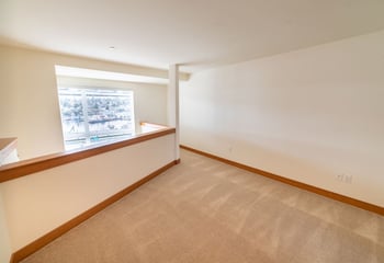 Bright rental living area at Union Bay Lofts, Seattle: open layout, large window, and modern kitchen.