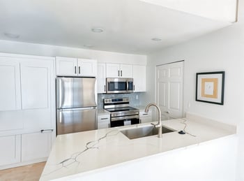 A kitchen with a white counter top and stainless steel appliances.