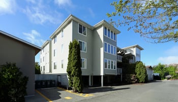 A large grey building with a parking lot in front.