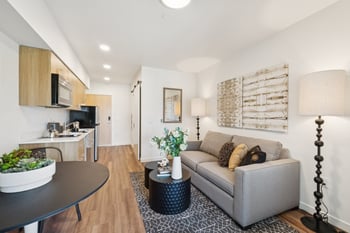 A modern living room with a grey couch and a black table.