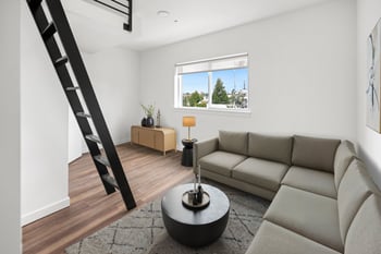 A living room with a grey sofa, a black coffee table, and a wooden floor.