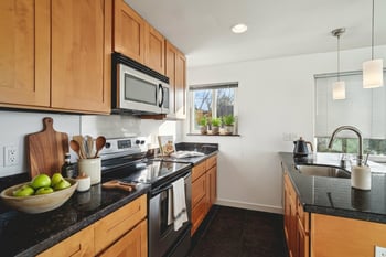 A kitchen with wooden cabinets and black countertops.