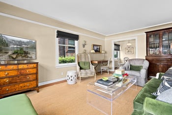 Spacious living room with green sofa, glass coffee table, desk area, and natural light at East Hi...