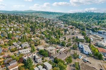 Aerial view over Fremont neighborhood in Seattle with ship canal, Aurora Bridge, and distant city skyline.