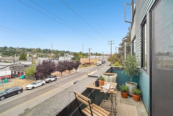 Private balcony with a bistro table and chairs and potted plants overlooking W Nickerson Street.