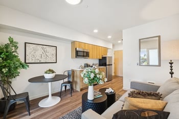 A living room with a grey couch, a white table, and a wooden cabinet.