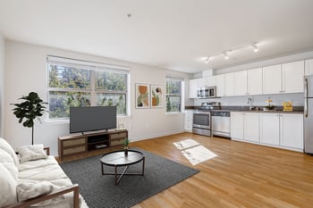 Bright living room at Gilbert House Apartments, Seattle, with large windows and modern seating.