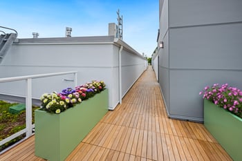 A wooden deck with green planters on the side.