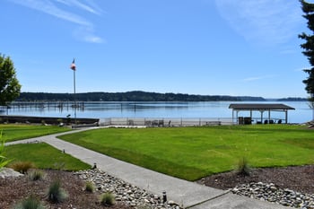 a grassy area with a flagpole and benches next to a body of water