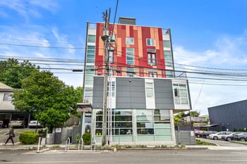 Bright studio apartment at Wallingford Studios, Seattle, featuring a kitchenette, large window, and hardwood floors.