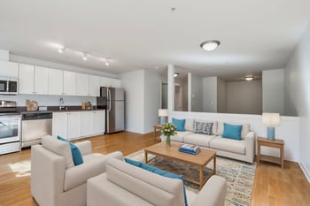 Bright living room at Gilbert House Apartments, Seattle, WA, with large windows and modern furnishings.
