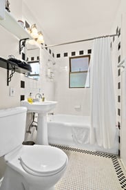 Bathroom with white pedestal sink, toilet, tub, and classic black and white tile at East Highland...