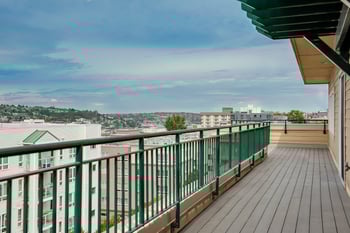 A balcony with a green railing overlooks a cityscape.