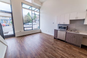 Bright living room at Lillehammer Apartments, Seattle, WA - sunlit space with hardwood floors and a large window.