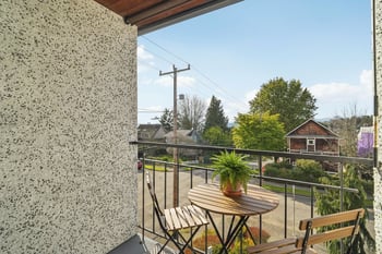 A balcony with a table and chairs overlooking a residential area.