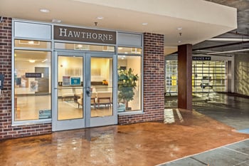 A Hawthorne storefront with a glass door and a brick wall.