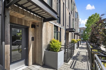 the facade of a building with a glass door and a sidewalk with plants
