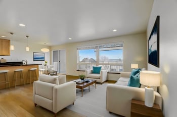 Living room with sofas, coffee table, and view of the kitchen.