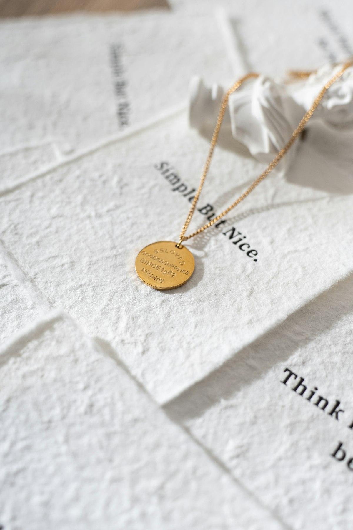 Dije circular en oro sobre papel con texto