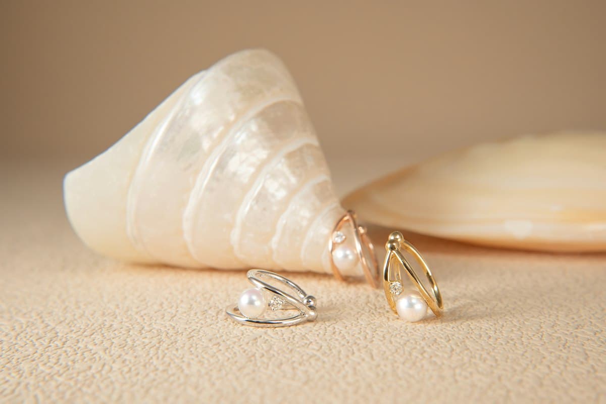 Argollas doradas junto a una concha sobre arena