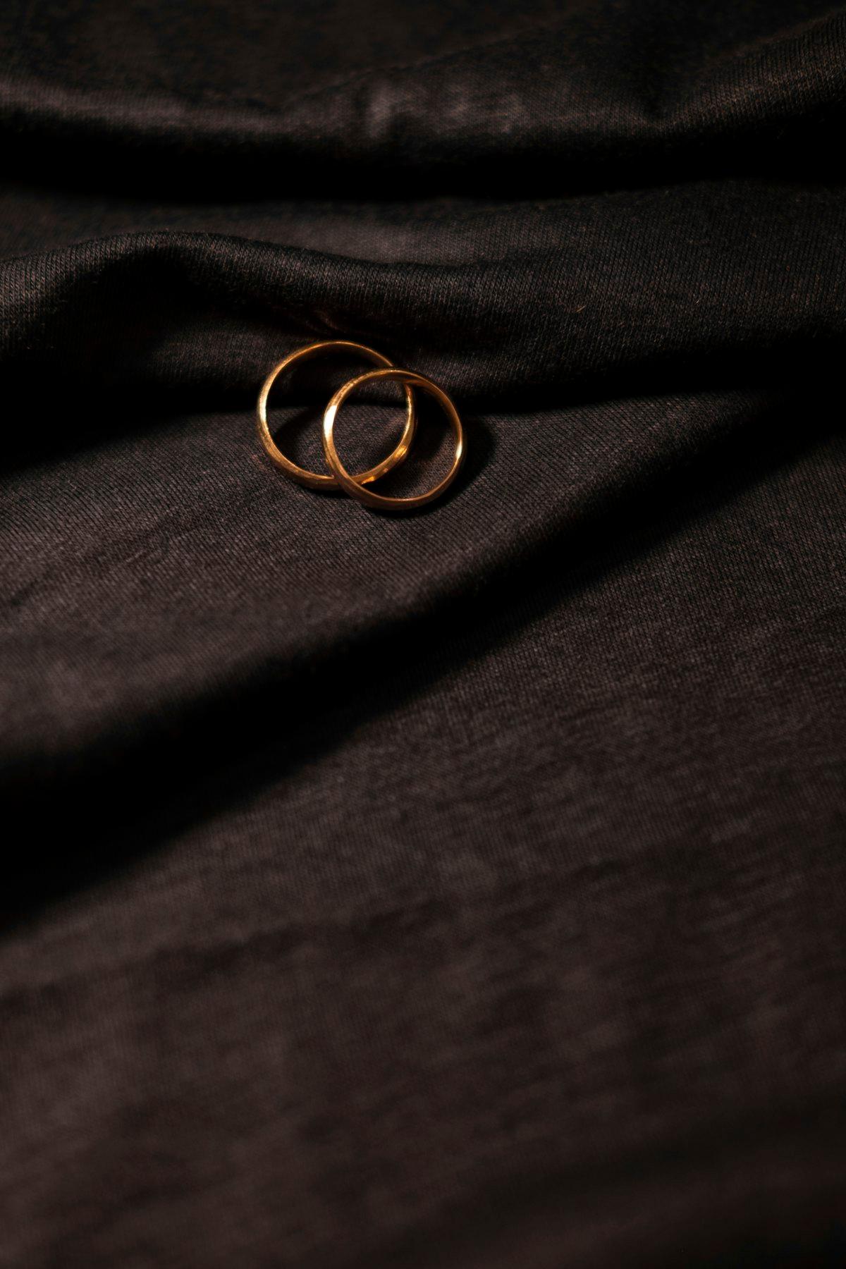 Dos anillos finos en oro entrelazados sobre tela negra