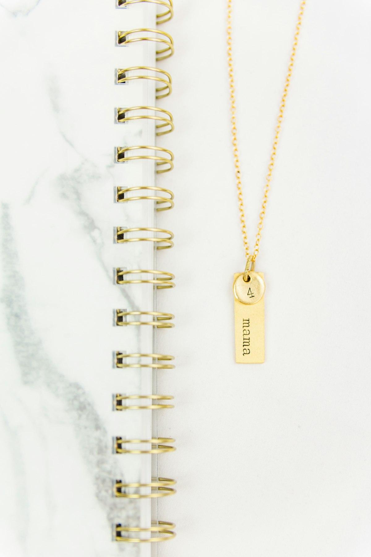 Cadena con dije personalizado grabado sobre una libreta
