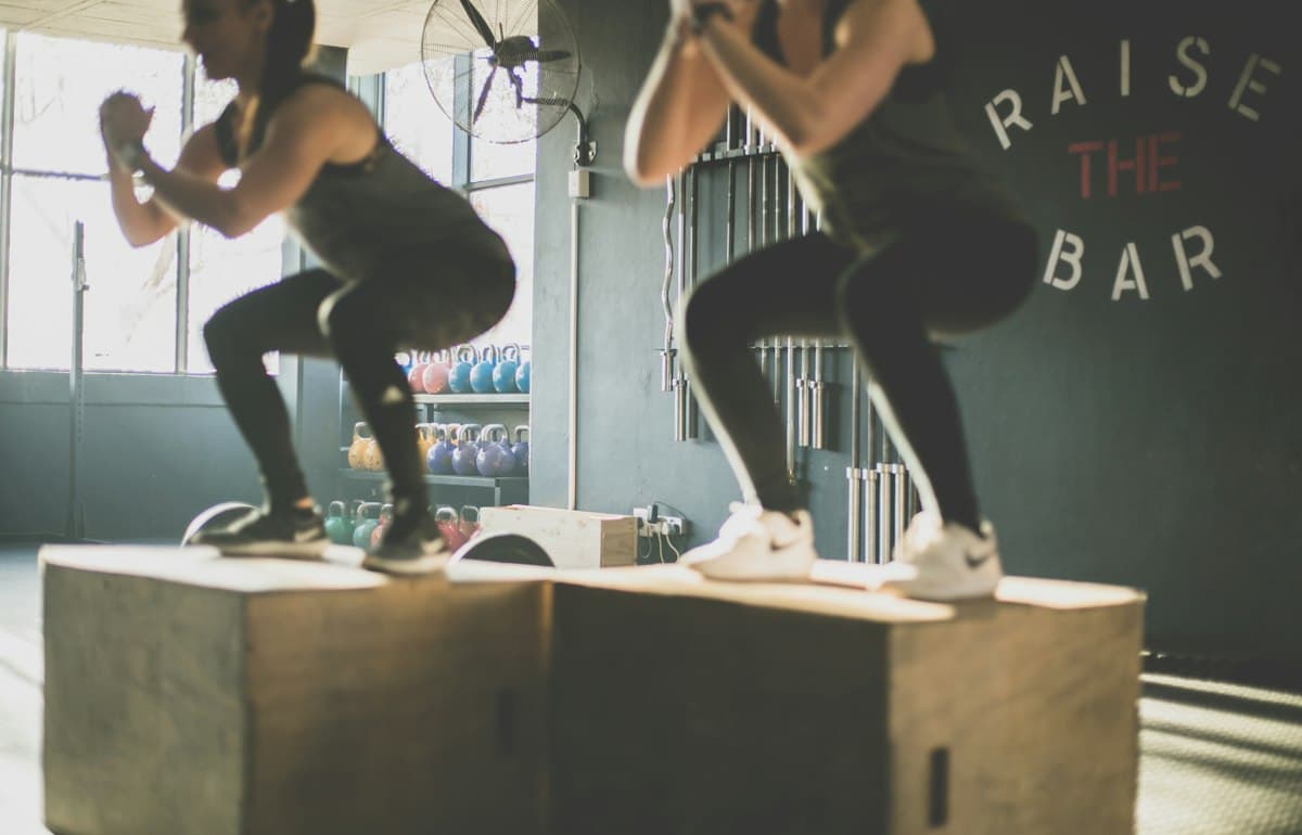Dos personas saltando sobre cajones en una sesión de entrenamiento