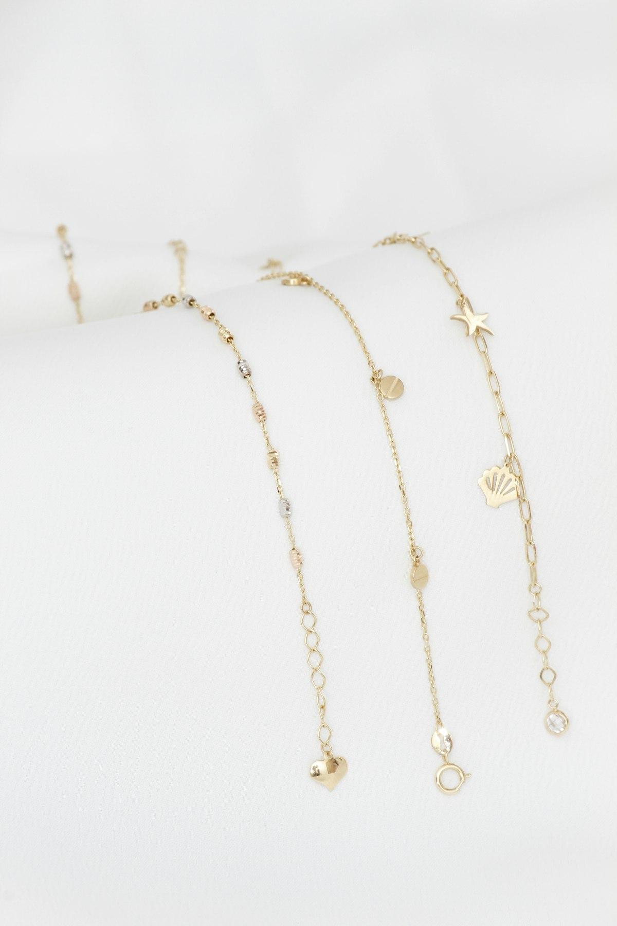 Pulseras de cadena fina con dijes sobre tela clara