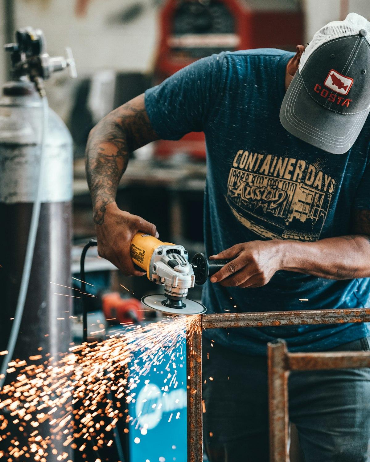 Hombre usando una amoladora angular con chispas en un taller