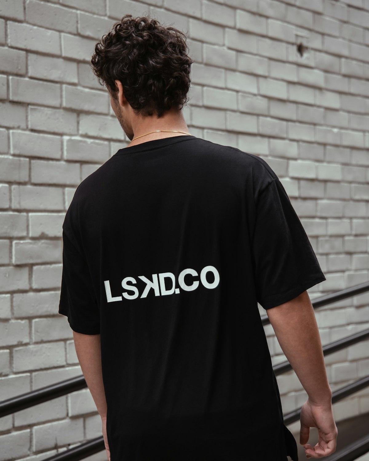 Hombre con franela oversized junto a una pared de ladrillo
