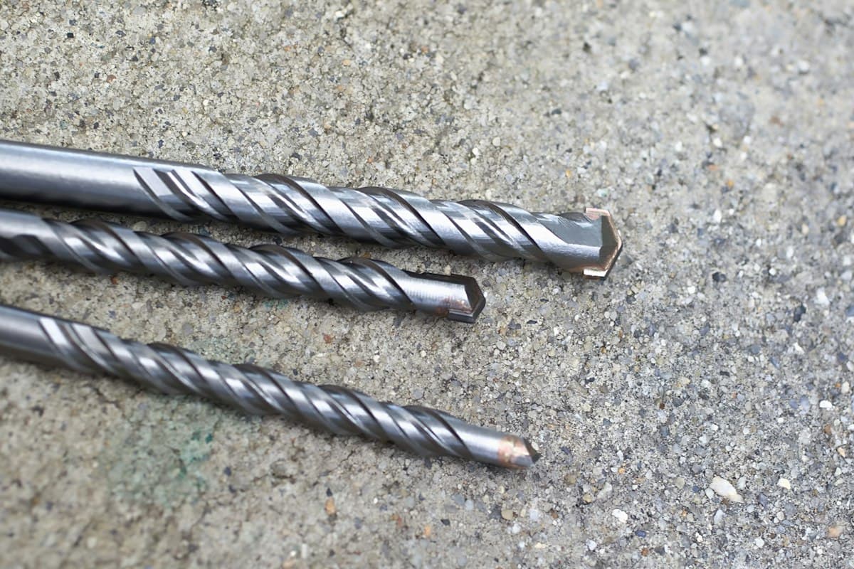 Tres brocas de metal sobre una superficie de concreto