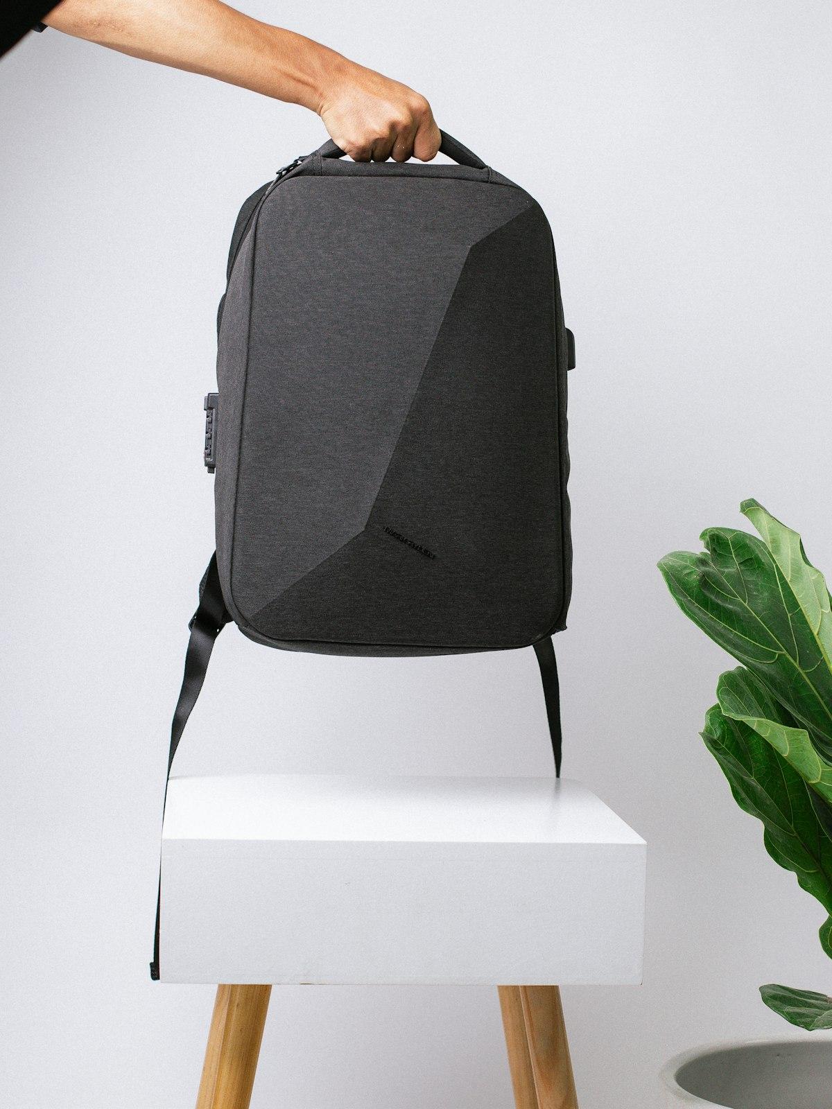 Morral deportivo gris sostenido con una mano