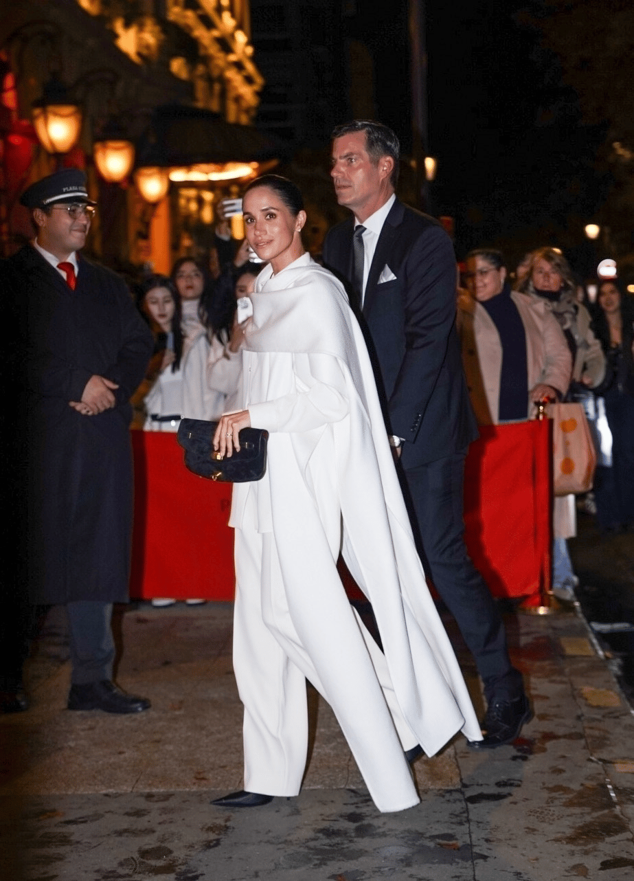 Wide frame, white cape walk, Paris Wide shot of Meghan Markle walking in an all white cape look during Paris Fashion Week 2025.