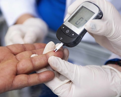 Doctor performing a finger-prick blood glucose test on a patient in Wales