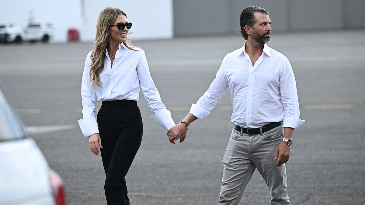 Donald Trump Jr. and his fiancee Bettina Anderson walk together on the tarmac at Teterboro Airport in late 2025