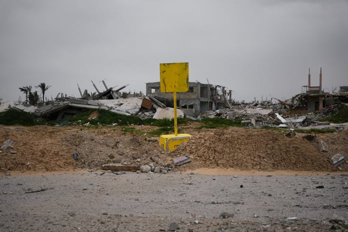 Palestinian family near yellow concrete blocks marking Israel's expanding buffer zone across the Gaza Strip