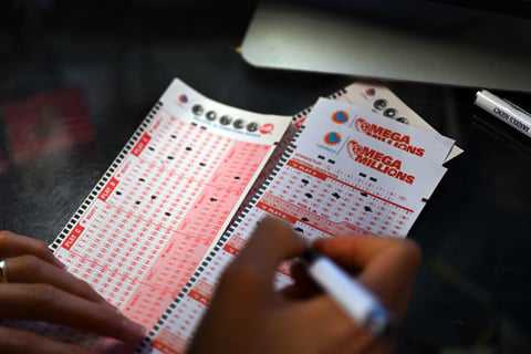 Customer fills out Mega Millions and Powerball lottery tickets at a gas station in California