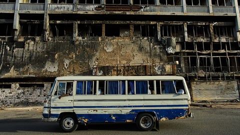 A bus drives past a destroyed hotel in Khartoum during Sudan's civil war
