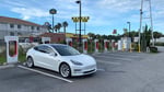 White Tesla Model 3 parked at a Supercharger station during Tesla Q2 2026 earnings quarter