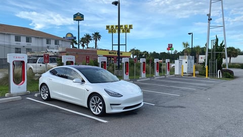 White Tesla Model 3 parked at a Supercharger station during Tesla Q2 2026 earnings quarter