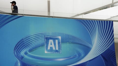 Visitors at the World Artificial Intelligence Conference in Shanghai passing an advertisement promoting AI applications