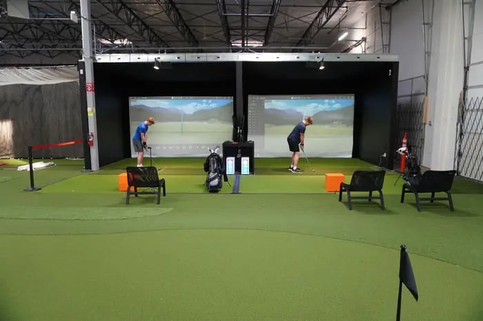Two golfers practicing at simulator