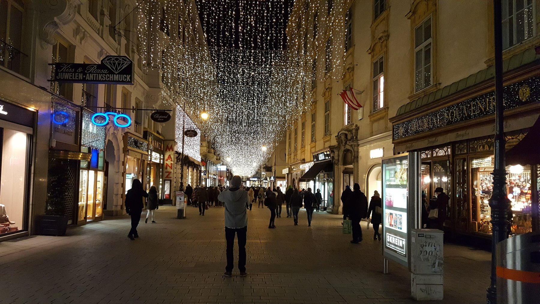 A street lined with shops and decorated with lights.