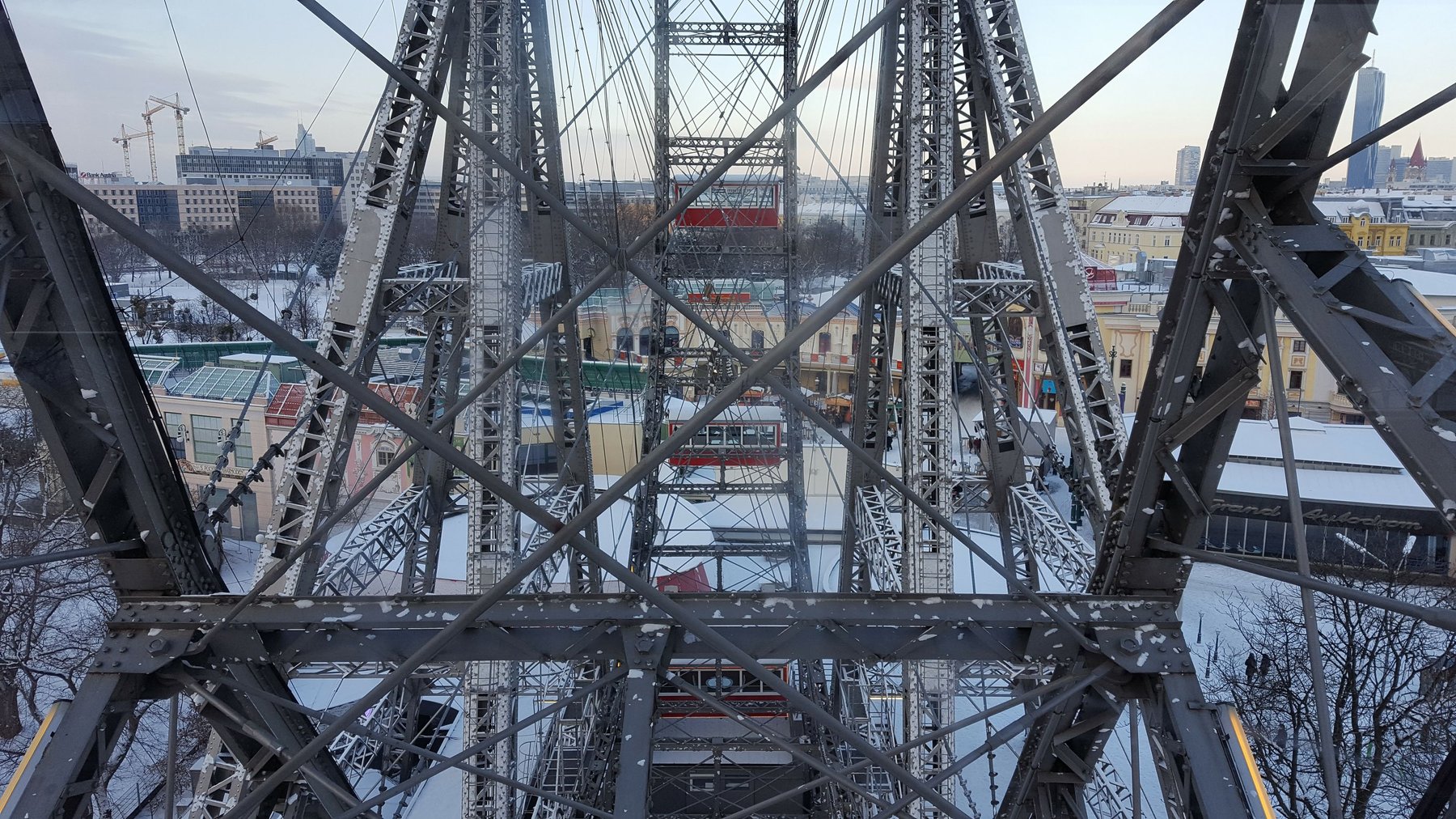 The metal scaffolding of a grand ferris wheel, viewed from inside one of the capsules.