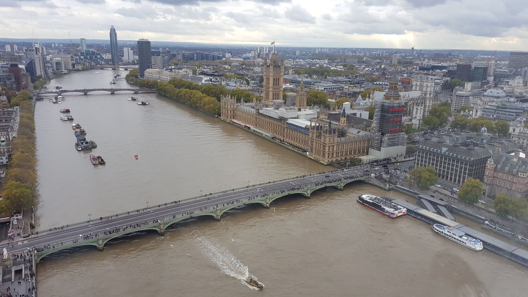 Bridges crossing the River Thames, viewed from high up. Big Ben is on the other side, surrounded by scaffolding.
