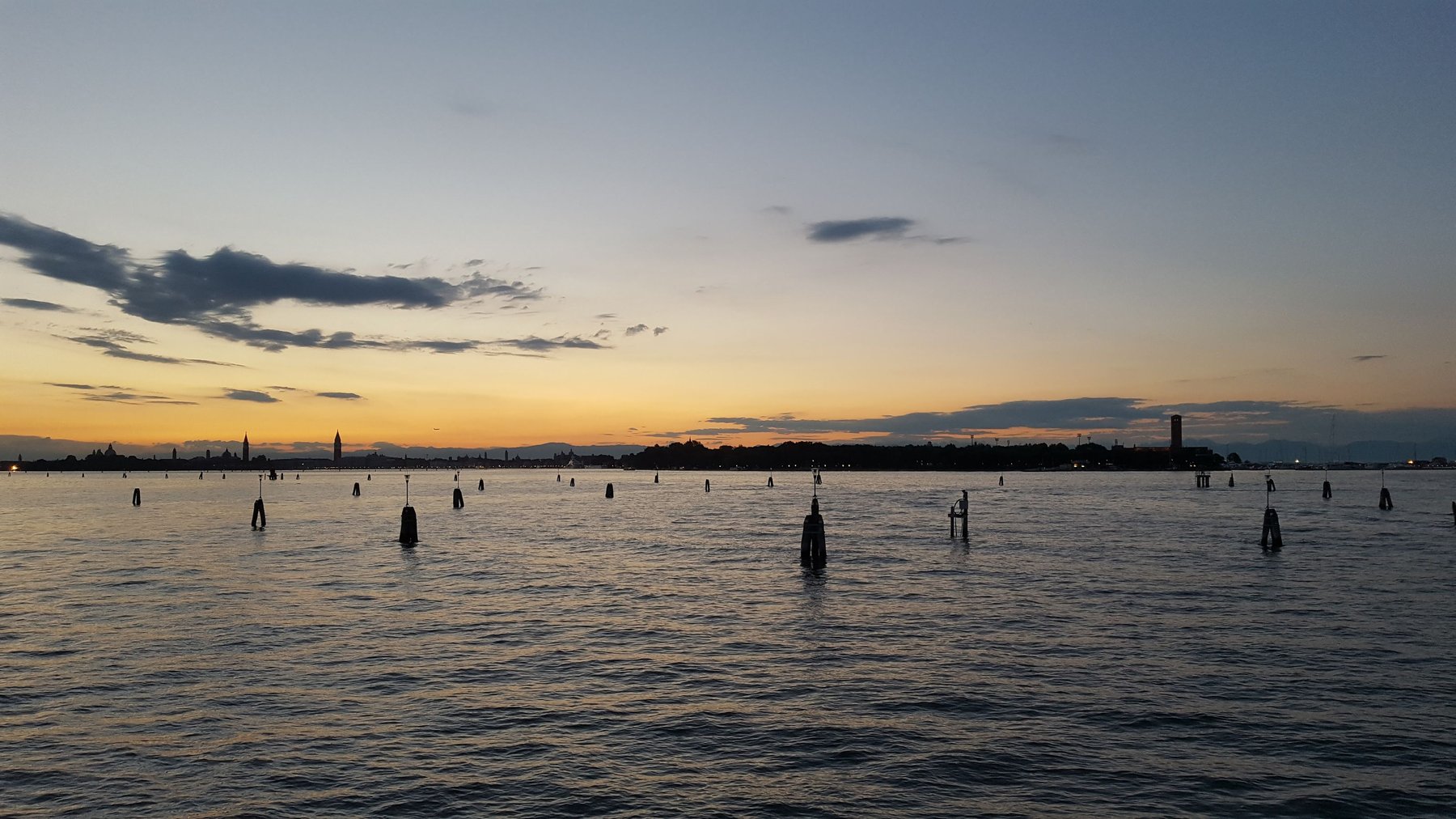 Open sea in the evening, littered with wooden posts.