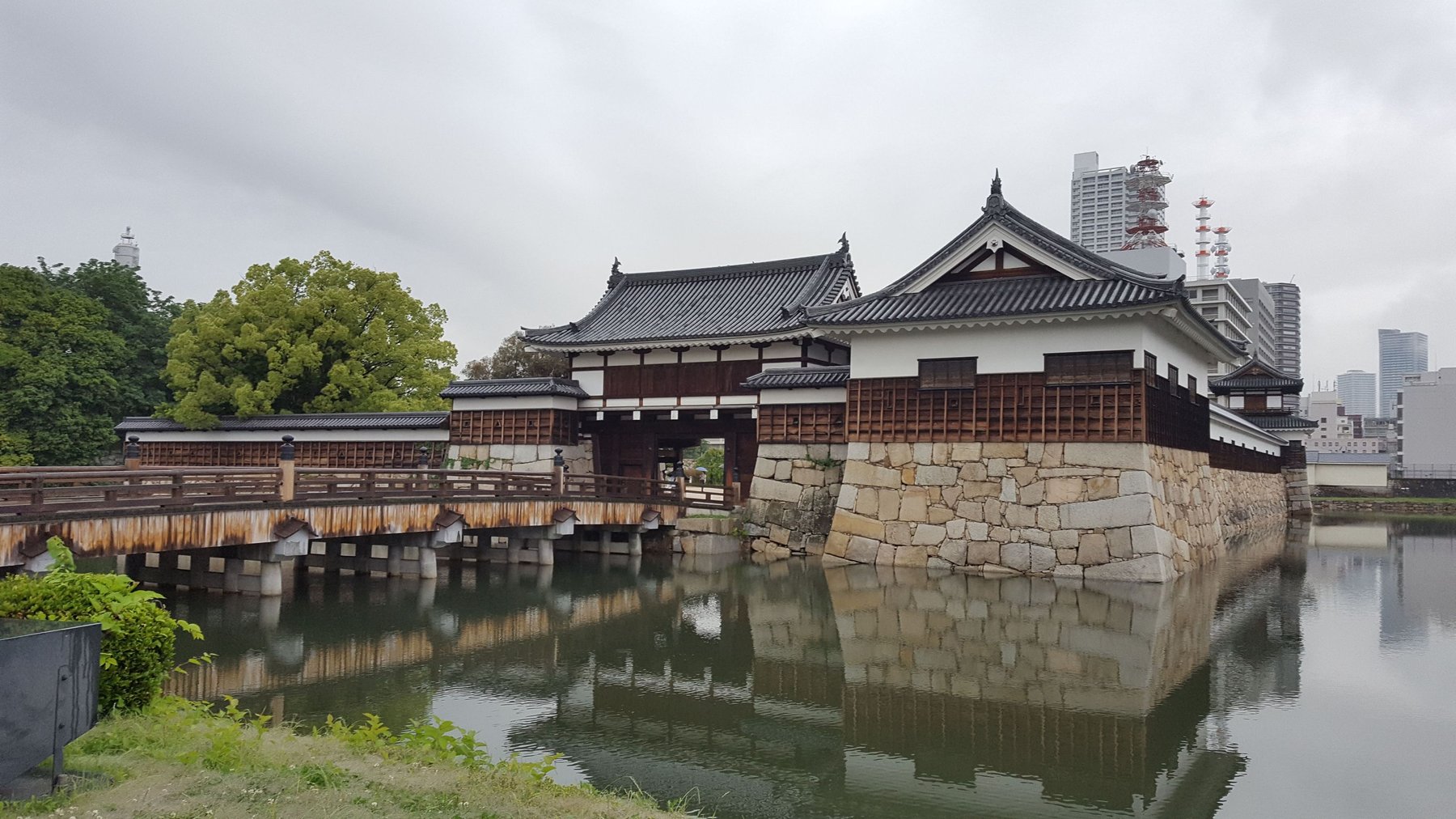 A bridge crossing a moat, with a decorative gatehouse on the other side.